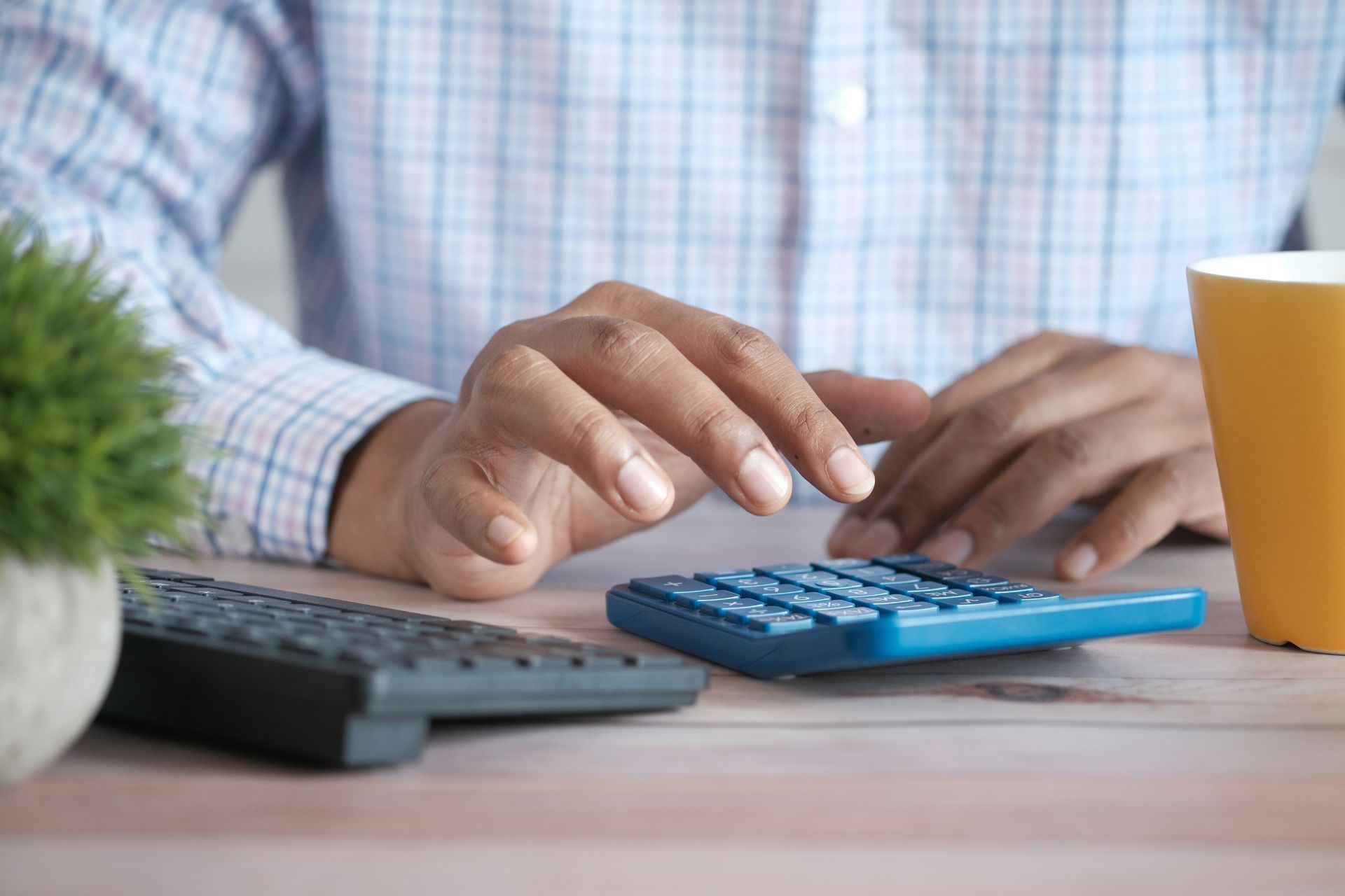 Close-up of hands using a calculator at a desk.