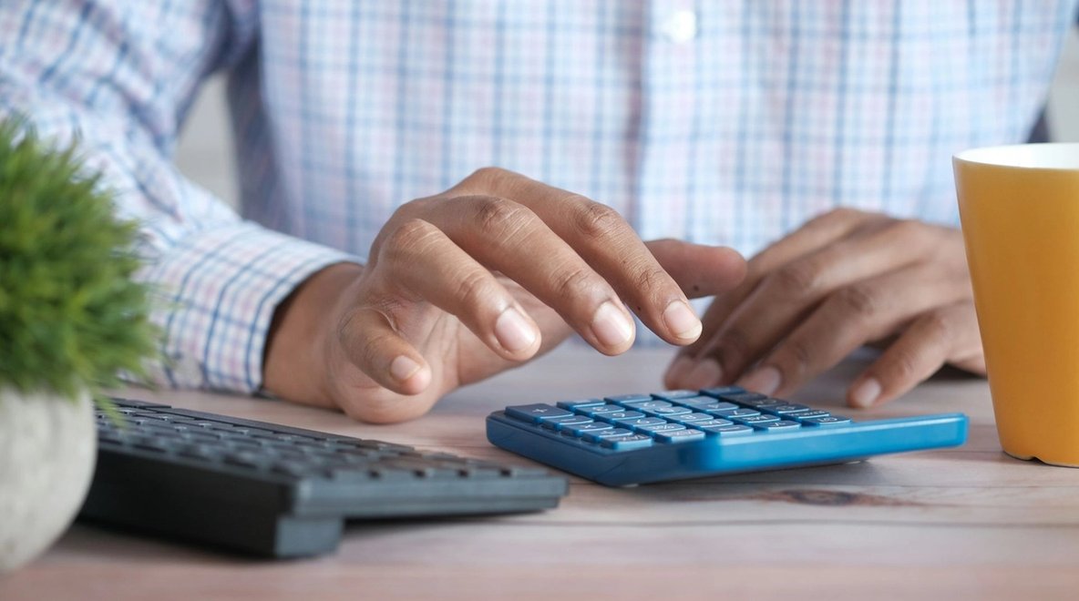 Close-up of hands using a calculator at a desk.