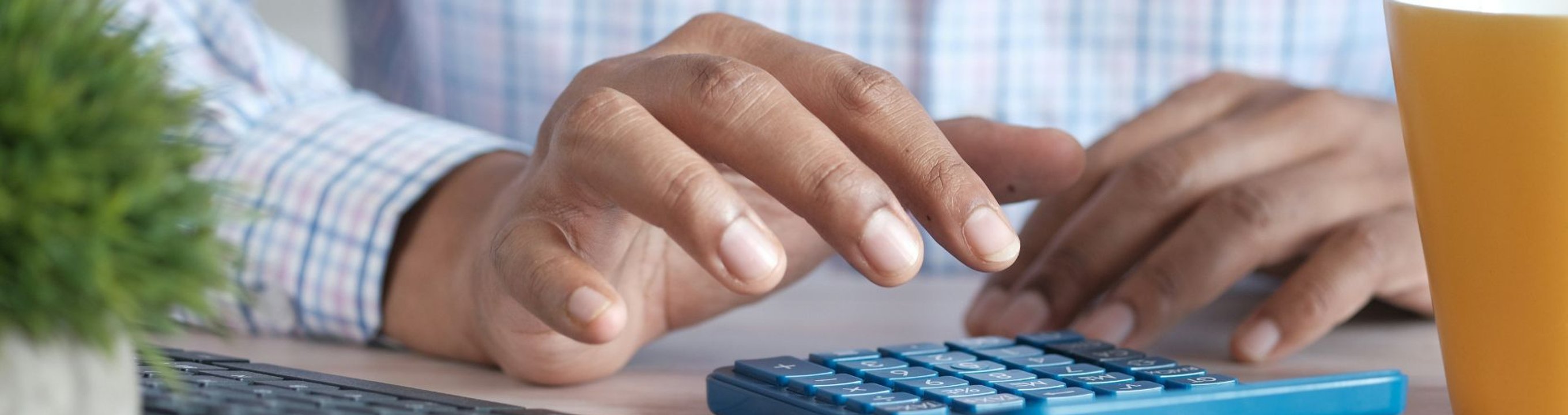 Close-up of hands using a calculator at a desk.