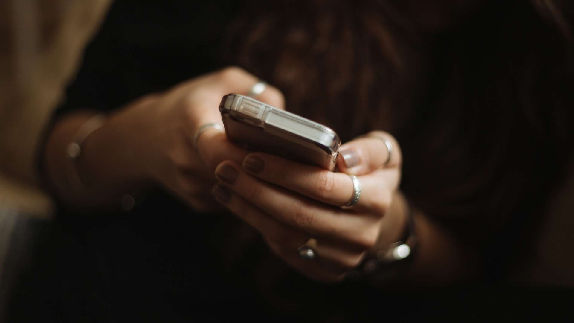 Hands holding a smartphone and typing on the screen.
