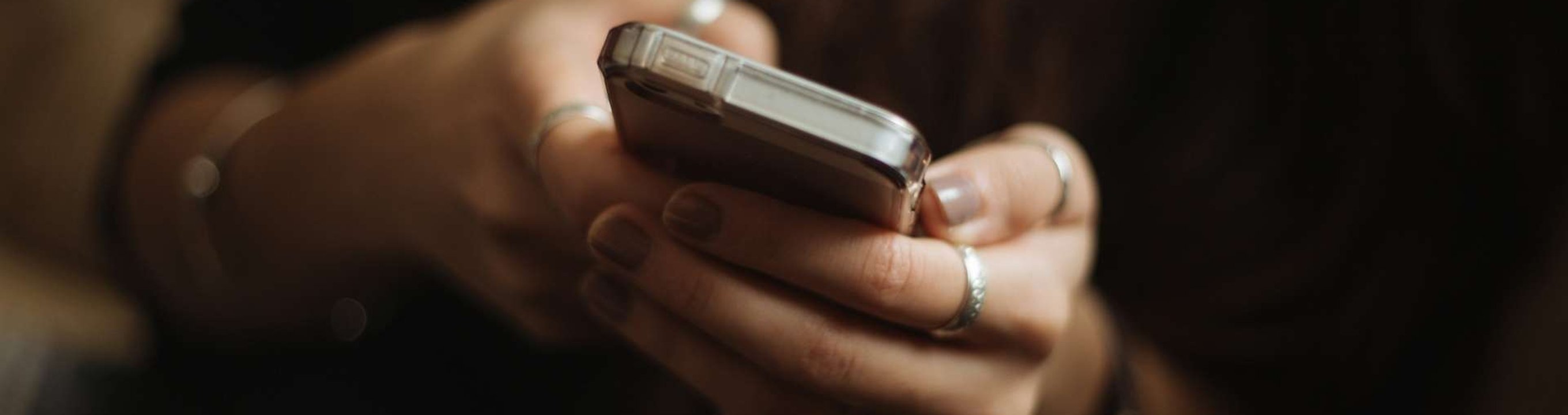Hands holding a smartphone and typing on the screen.