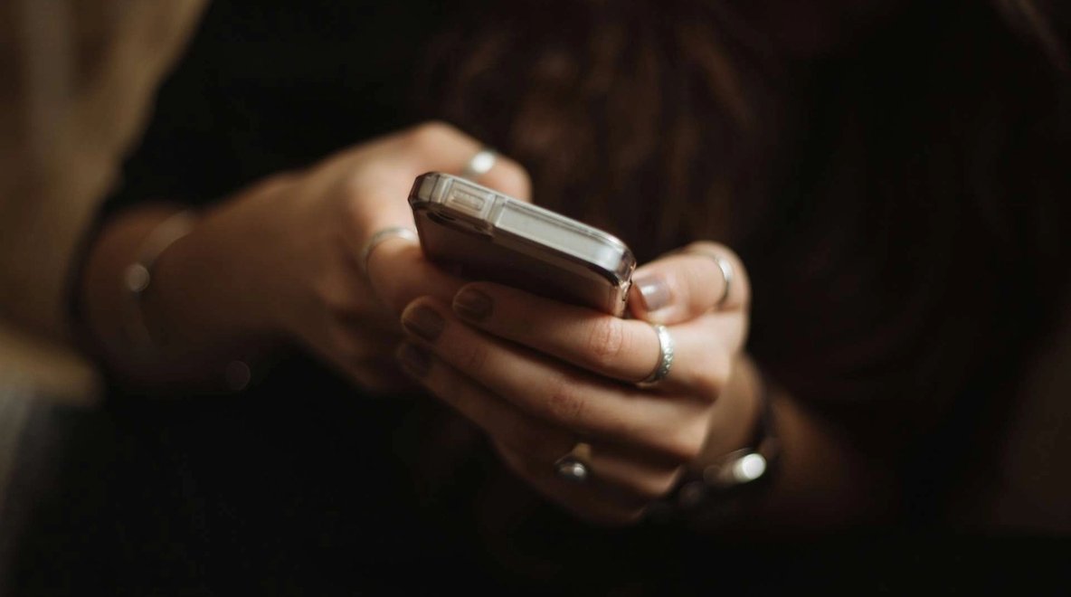 Hands holding a smartphone and typing on the screen.