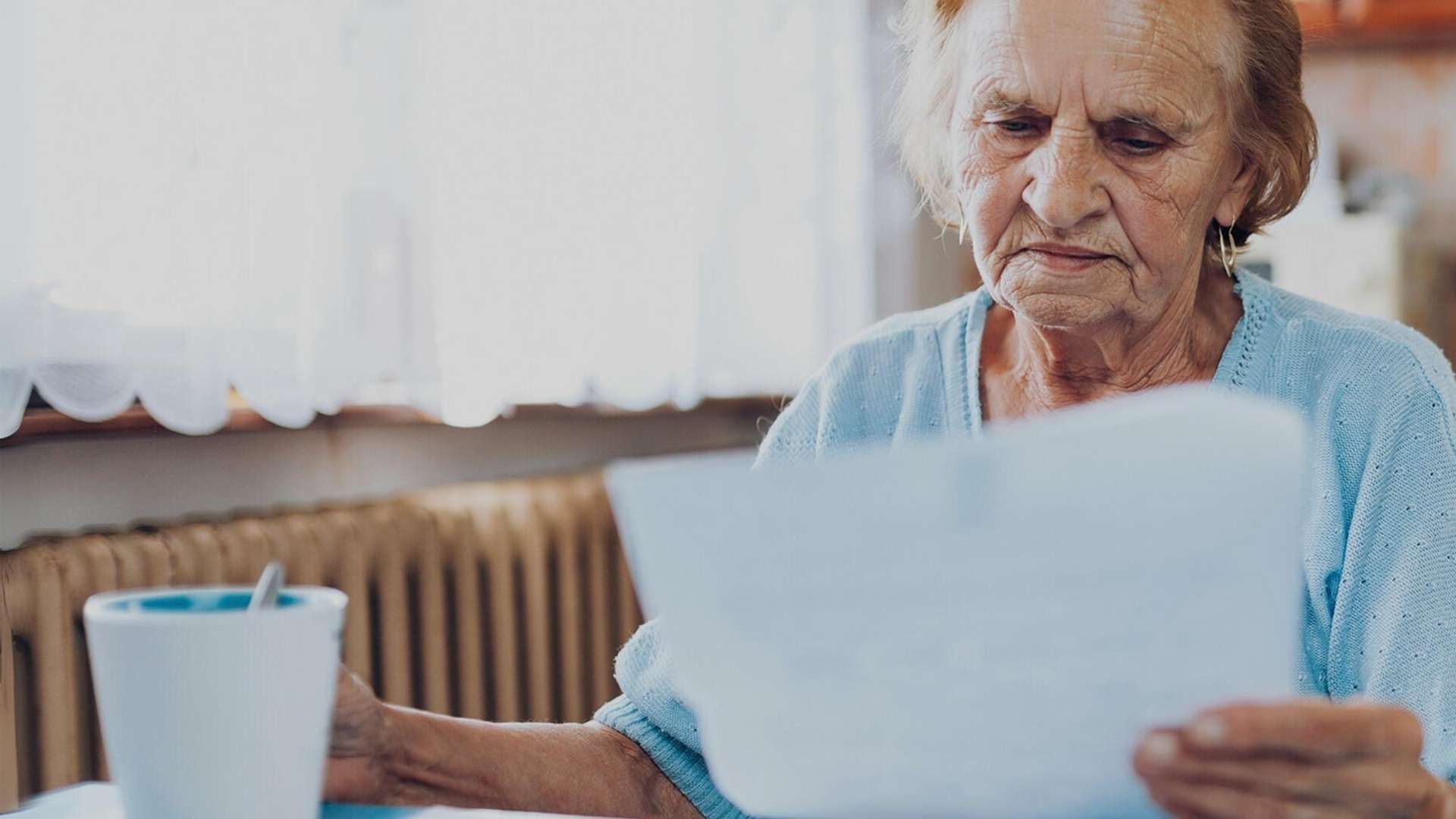 Older person reviewing a document at a table.