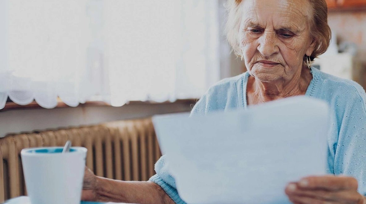 Older person reviewing a document at a table.