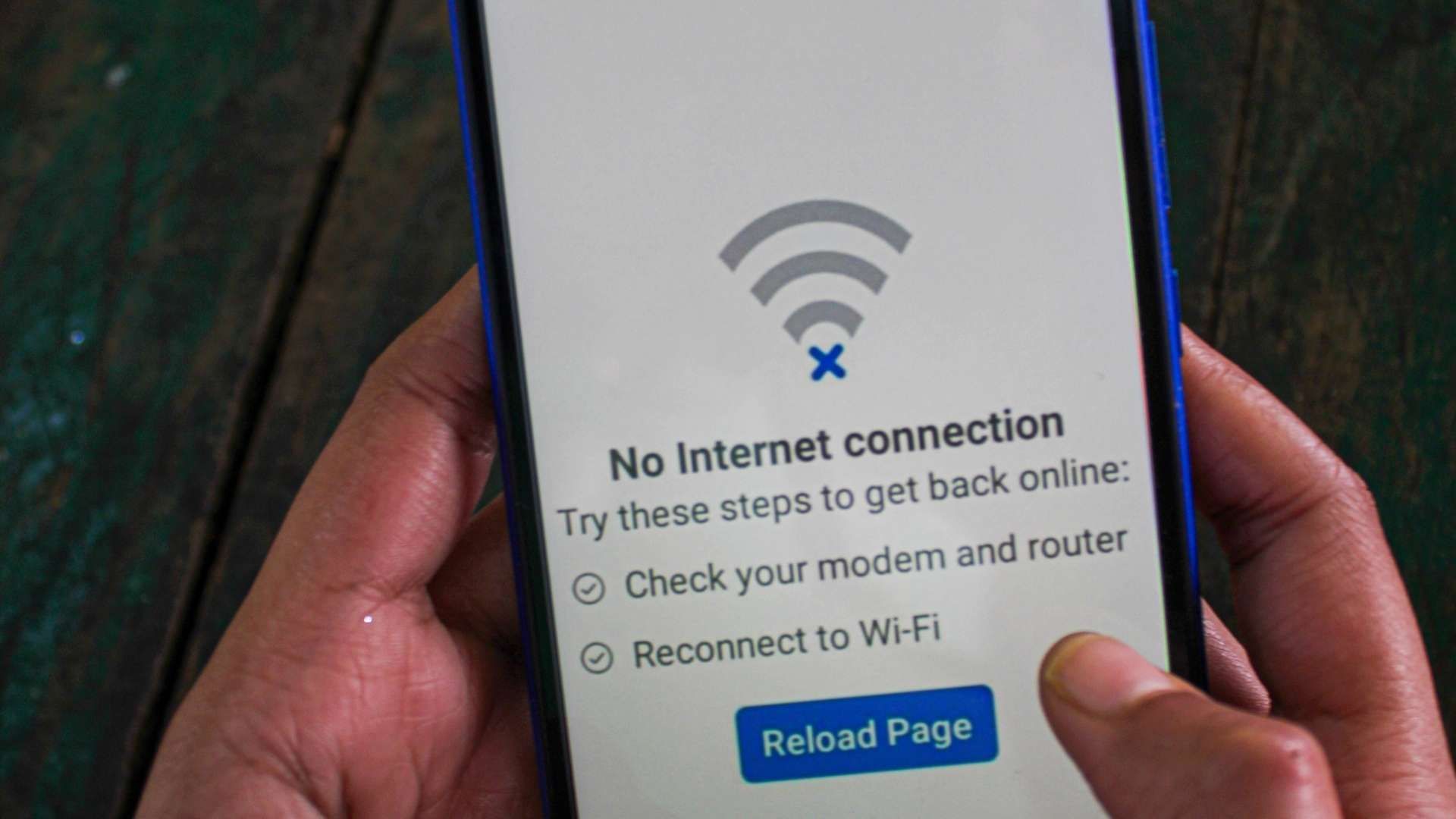 Hand holding a smartphone displaying no internet connection message.