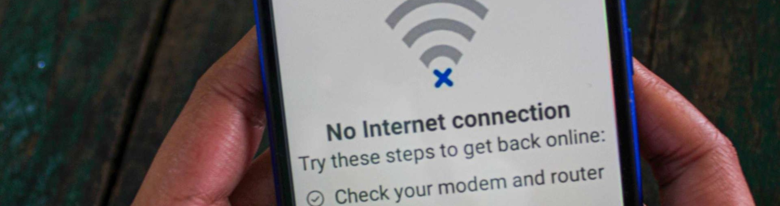 Hand holding a smartphone displaying no internet connection message.