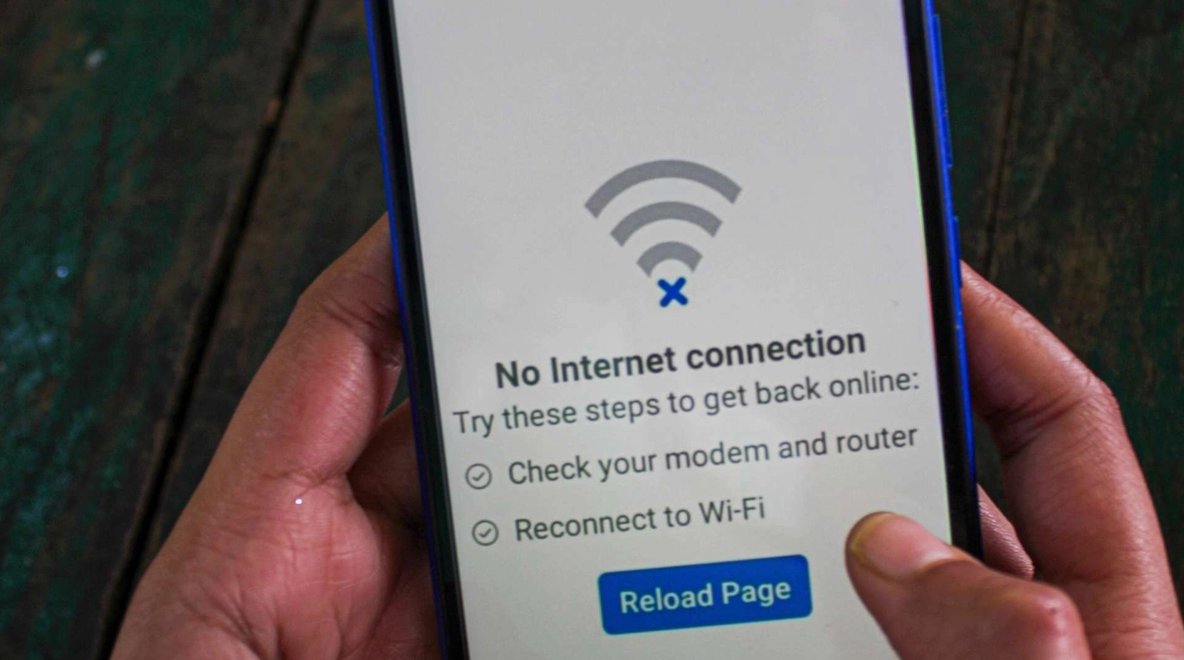 Hand holding a smartphone displaying no internet connection message.