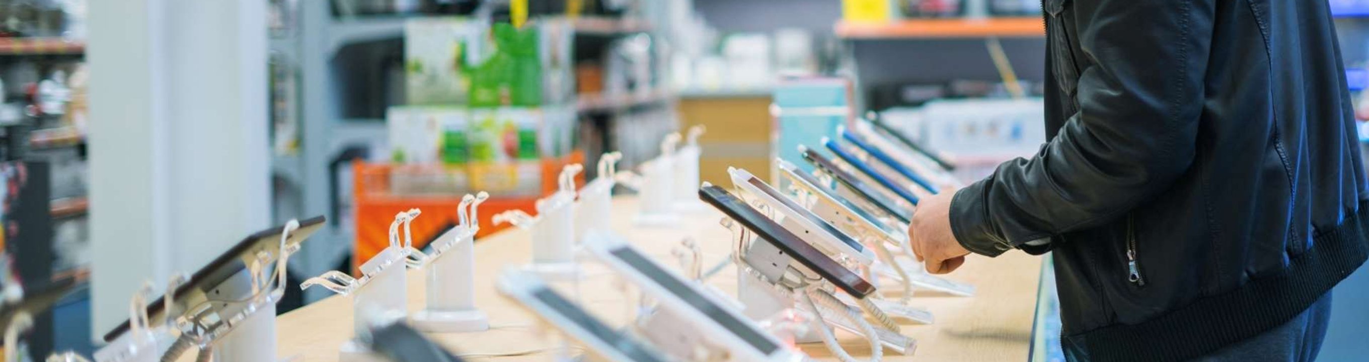 Person standing at a display table in a store looking at smartphones