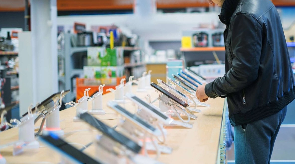 Person standing at a display table in a store looking at smartphones