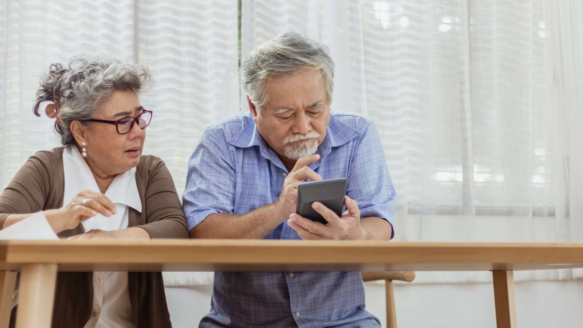Two people sitting side by side looking at a smartphone together.