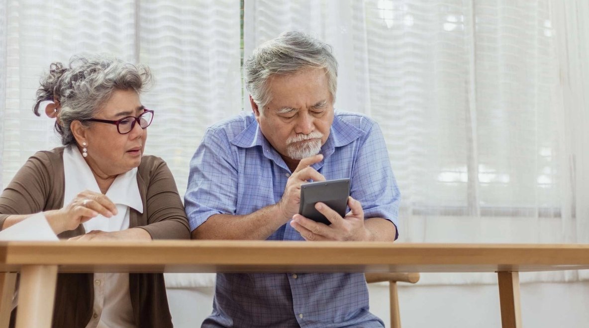 Two people sitting side by side looking at a smartphone together.