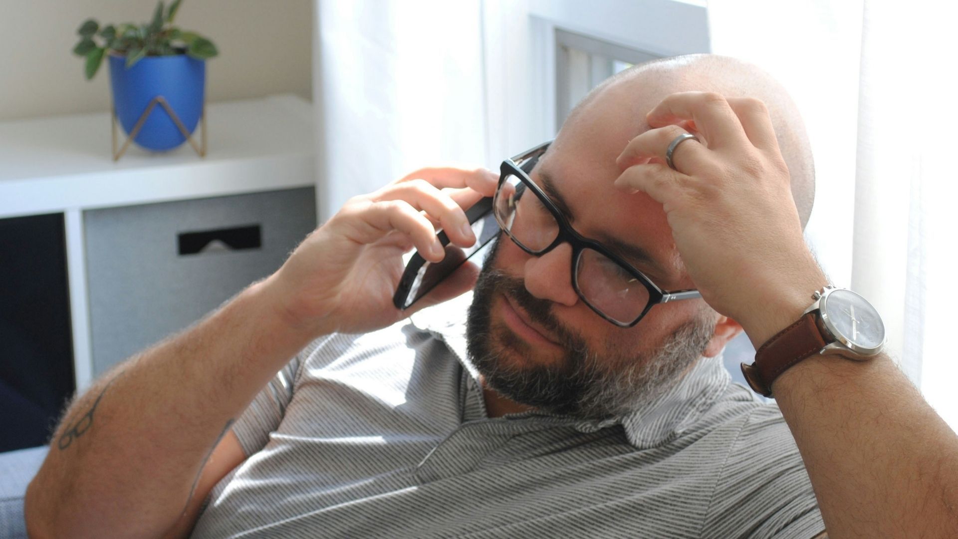 Person sitting on a chair holding a smartphone to their ear.