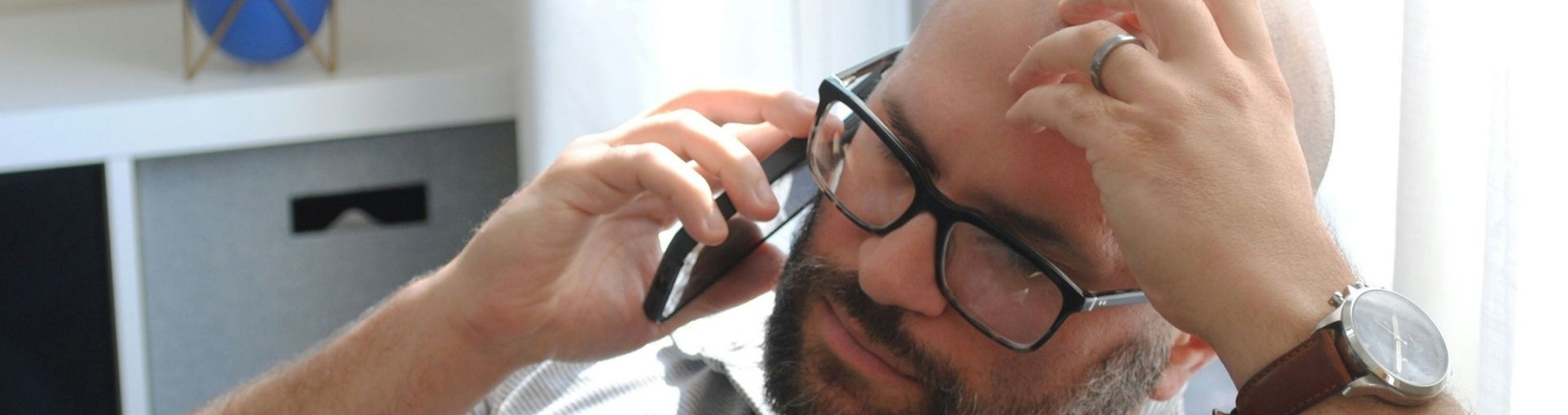 Person sitting on a chair holding a smartphone to their ear.