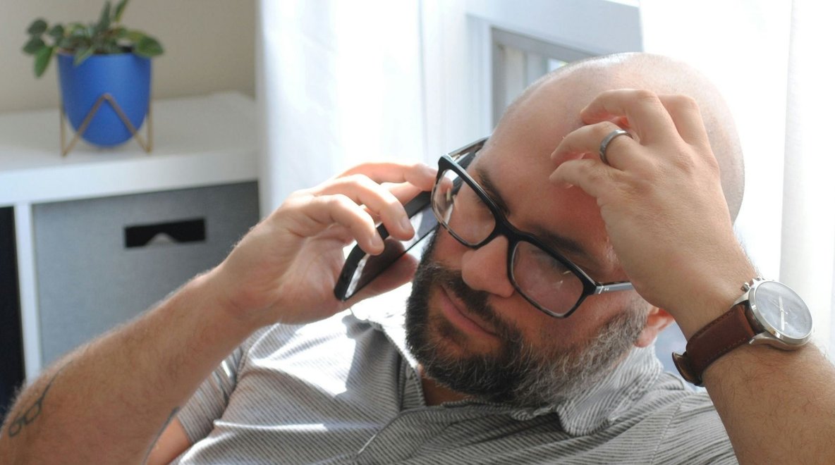 Person sitting on a chair holding a smartphone to their ear.