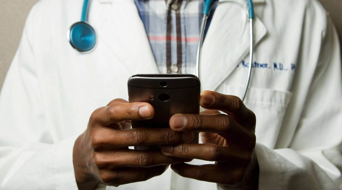 A doctor types on his mobile phone