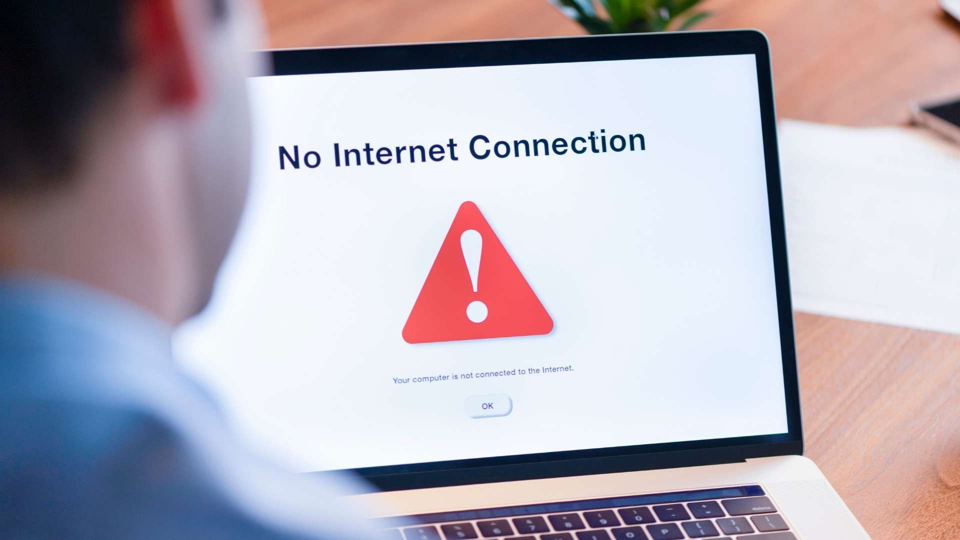 Person using a laptop displaying a no internet connection message on screen