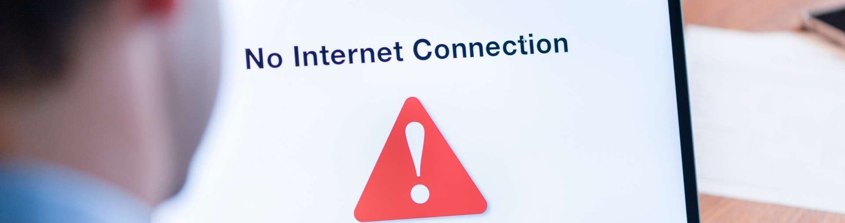 Person using a laptop displaying a no internet connection message on screen