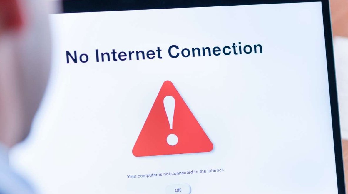 Person using a laptop displaying a no internet connection message on screen