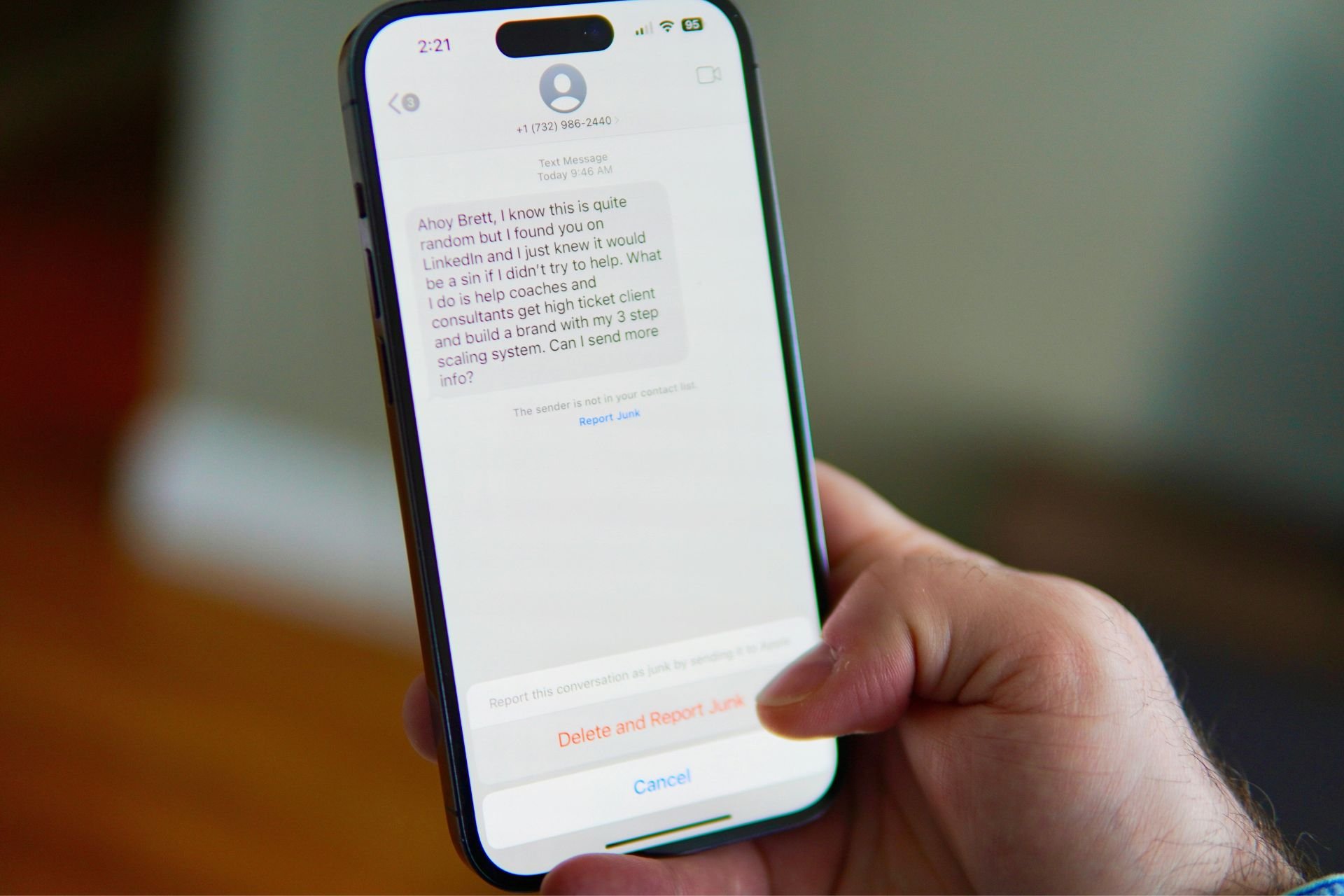 Close-up of a person holding a smartphone showing a text message on the screen.