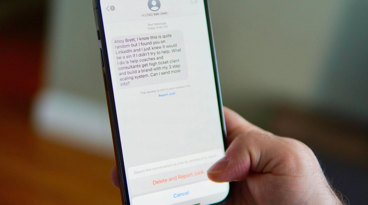Close-up of a person holding a smartphone showing a text message on the screen.