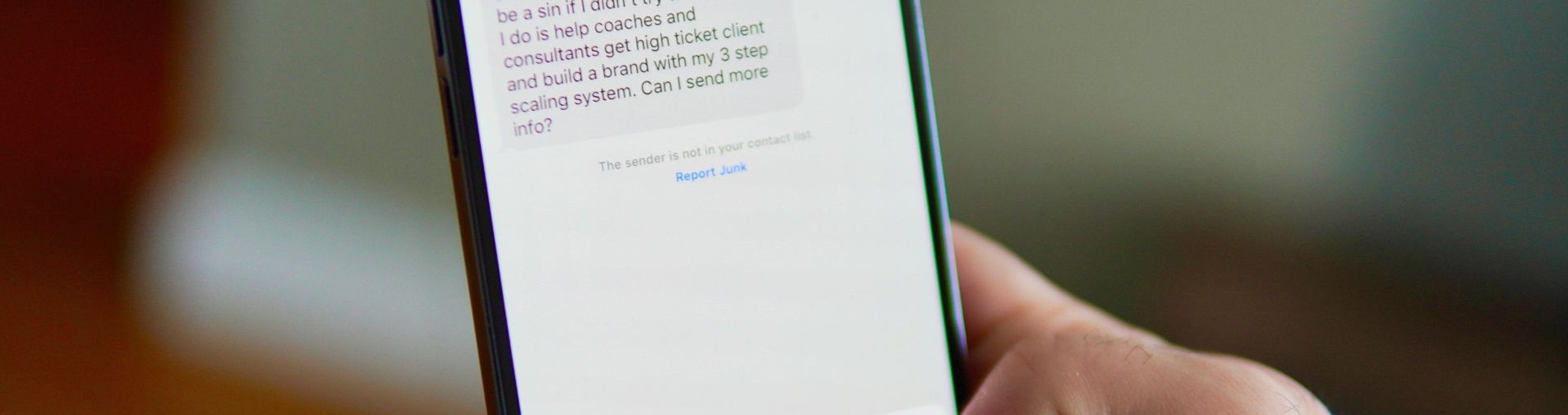 Close-up of a person holding a smartphone showing a text message on the screen.