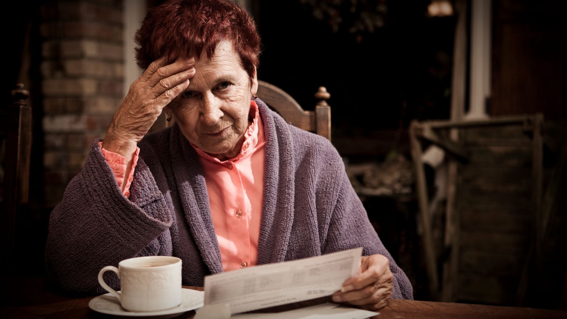 Person reviewing a paper bill or statement and looking worried.