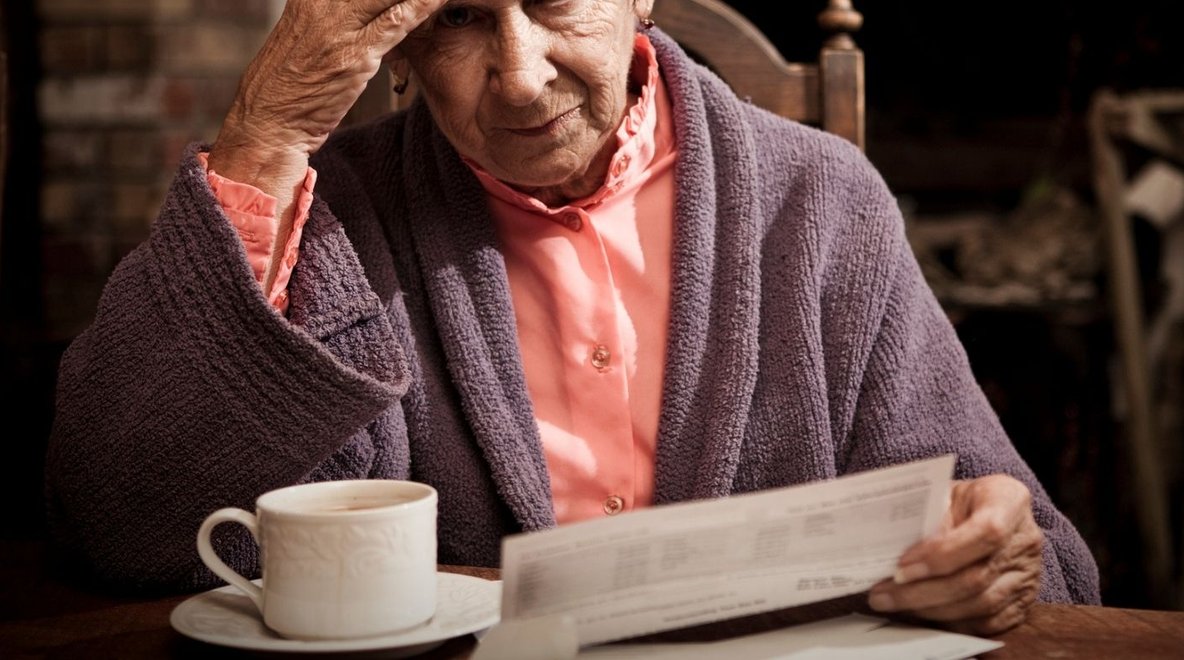 Person reviewing a paper bill or statement and looking worried.