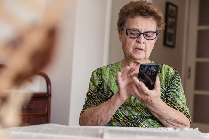 Person sitting at a table using a smartphone.