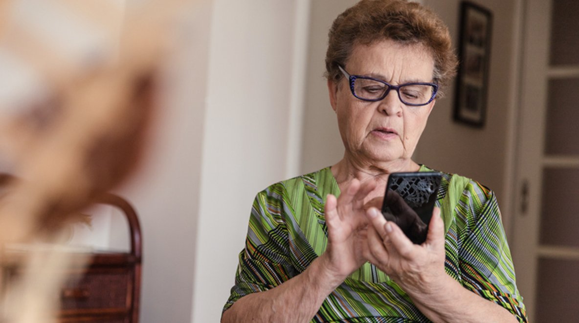 Person sitting at a table using a smartphone.