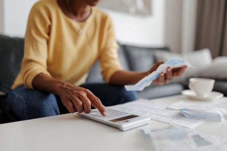 Person using a calculator and reviewing bills at a table.