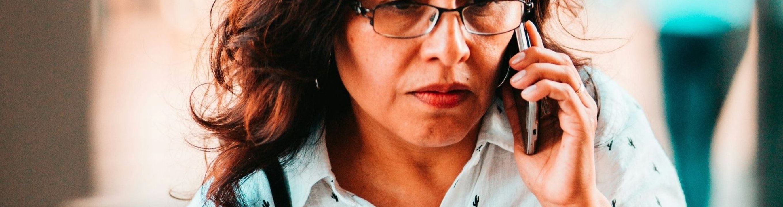 Person looking worried while holding a mobile phone to their ear while standing outside.