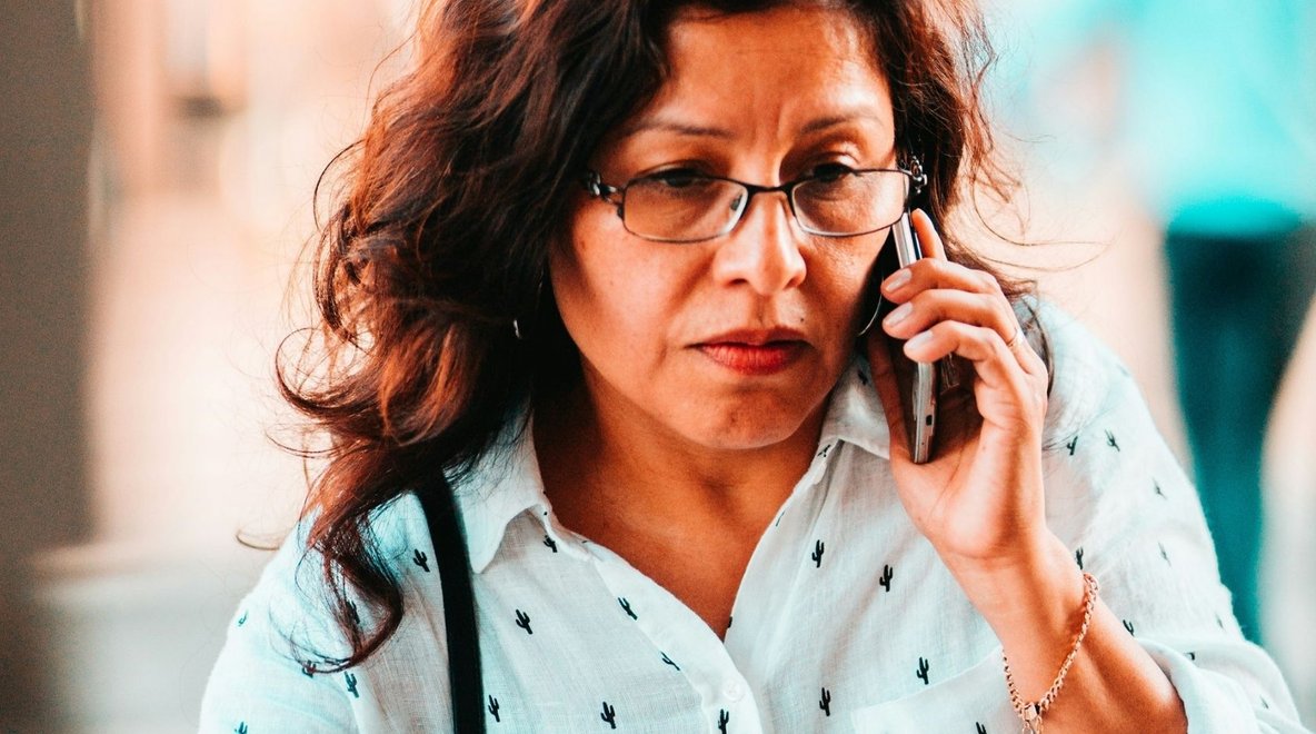 Person looking worried while holding a mobile phone to their ear while standing outside.