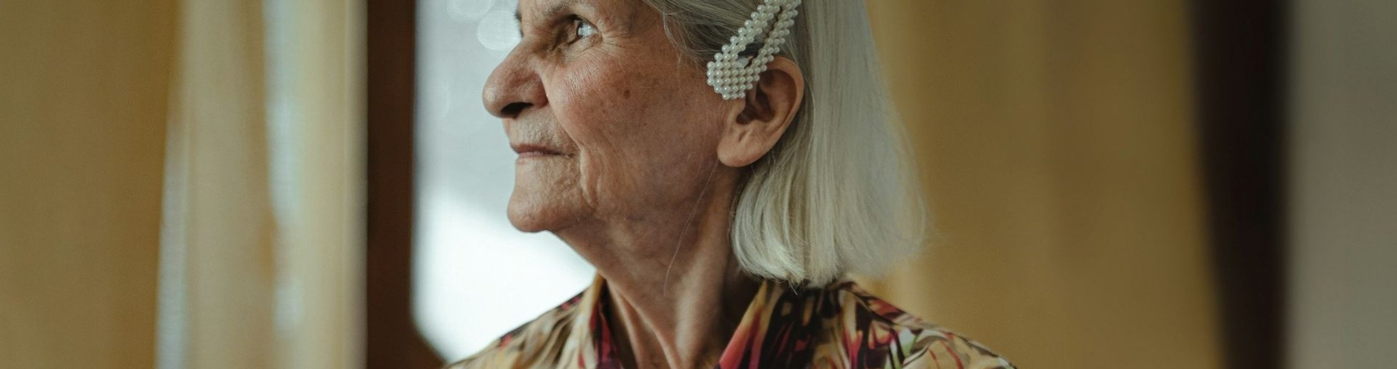 Older person looking out a window inside a home.