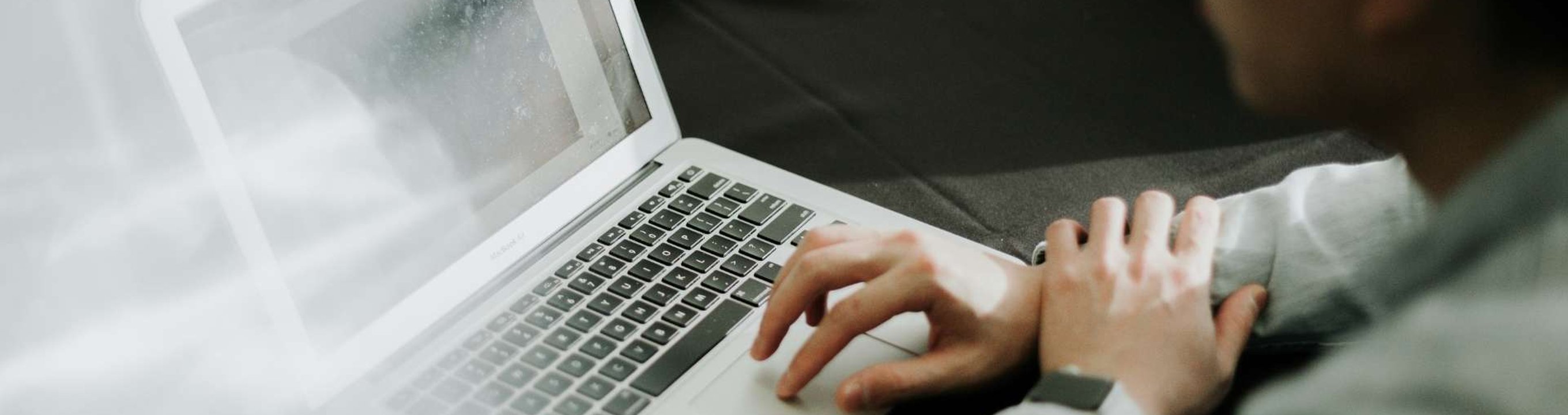 Person working on a laptop at a table with another laptop visible nearby