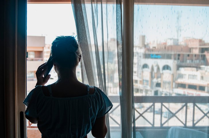 A person (woman) talking on a phone looking outside the window