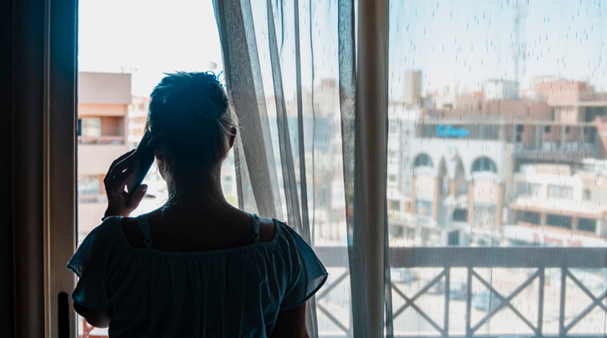 A person (woman) talking on a phone looking outside the window
