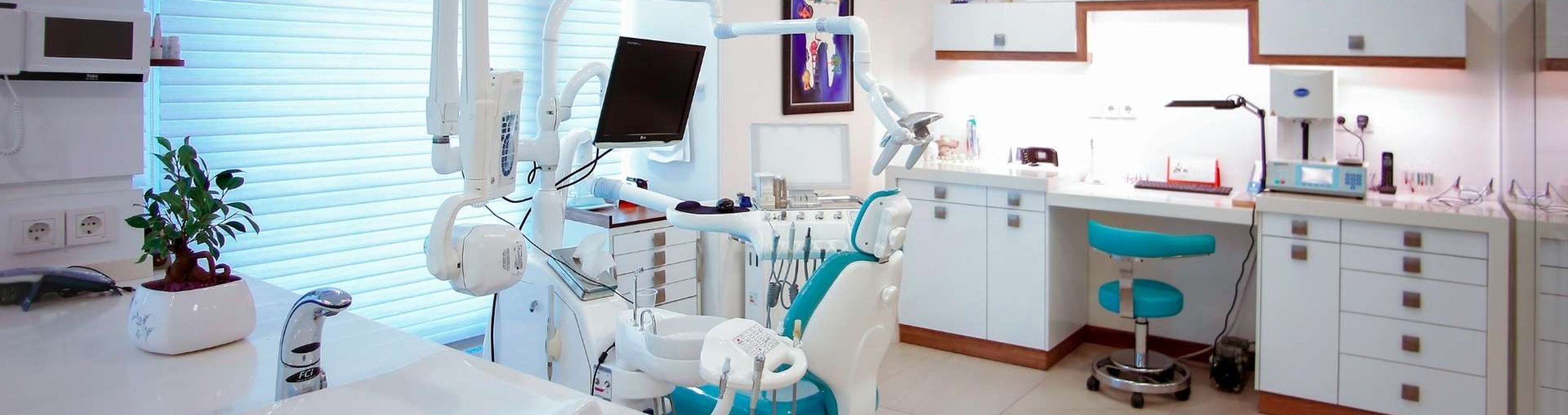 Empty dental clinic room with chair, equipment and workstation.