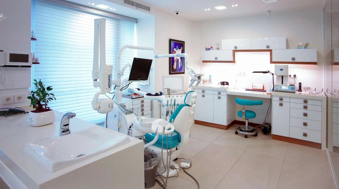 Empty dental clinic room with chair, equipment and workstation.