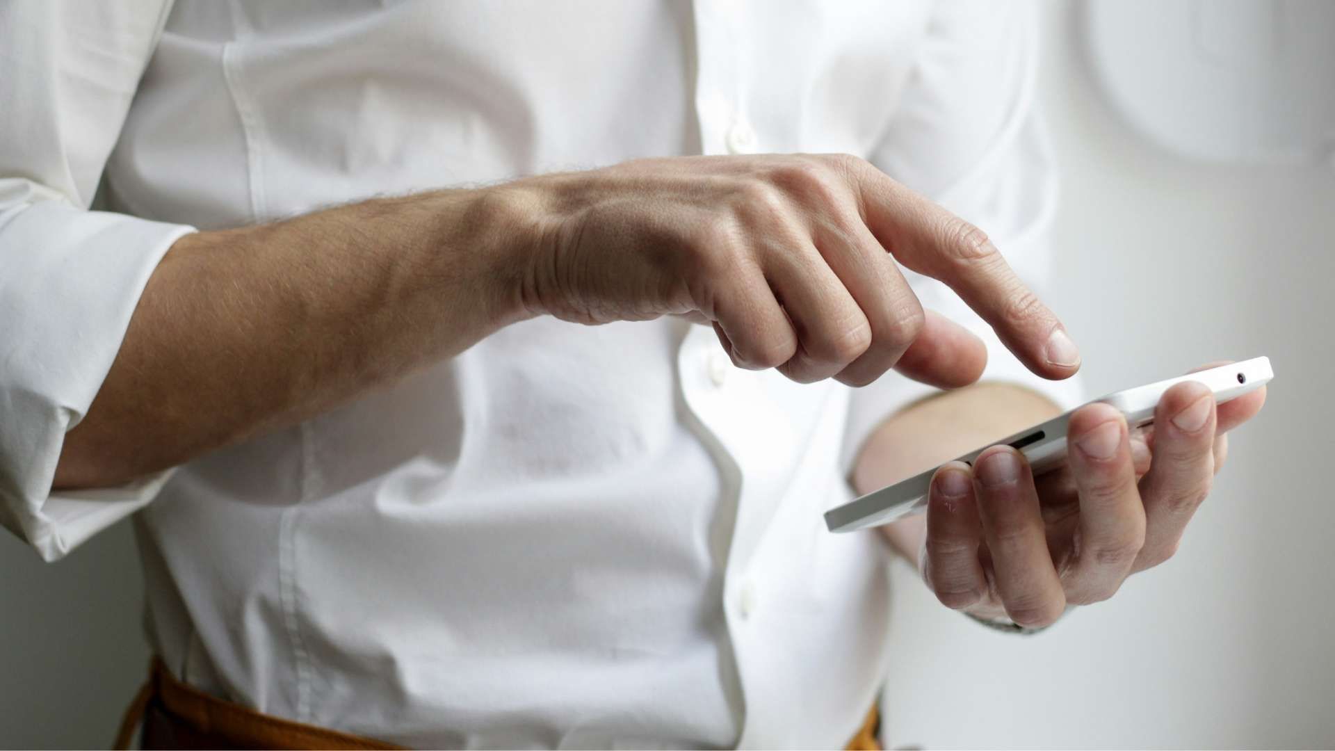 Hand pointing at and using a smartphone.