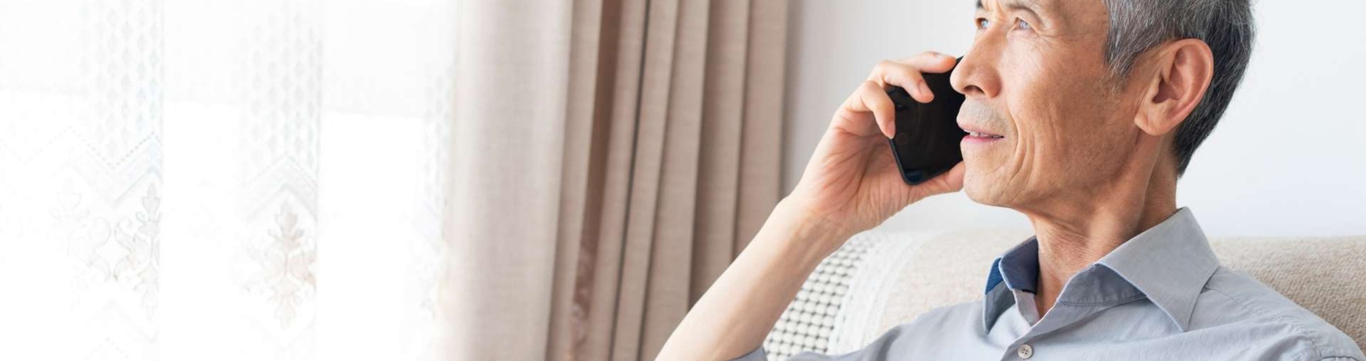 Person holding a mobile phone to ear while sitting beside a window.