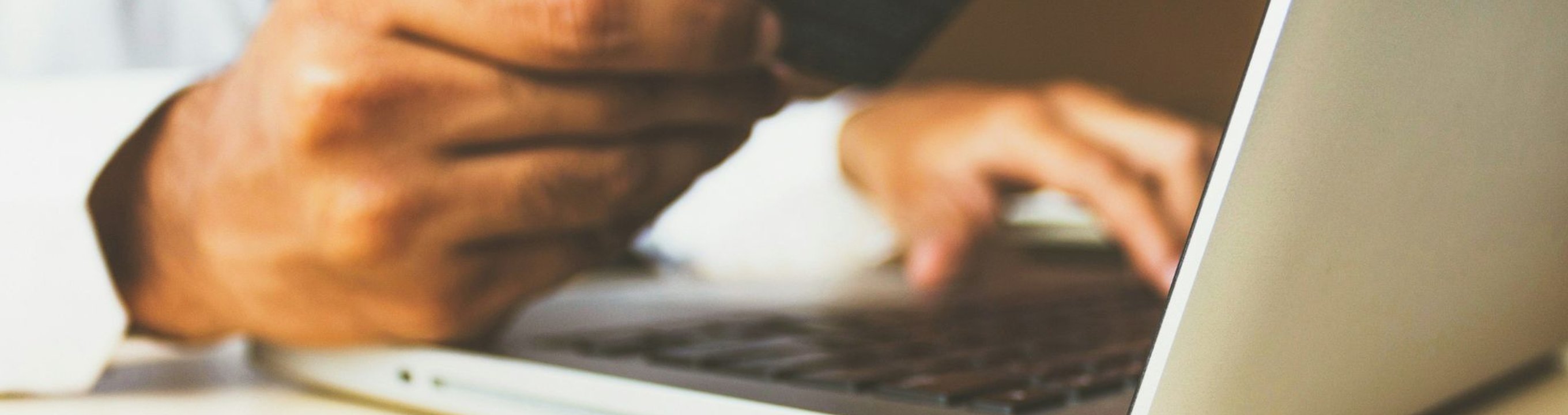 Close-up of a person holding a credit card and using a laptop.