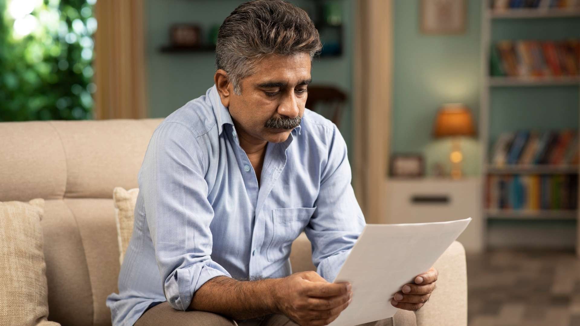 Person sitting on a couch reviewing a document in a living room