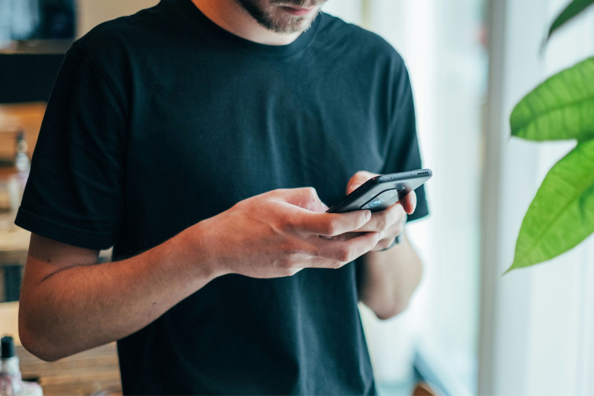 Close-up of a person holding and using a smartphone indoors.
