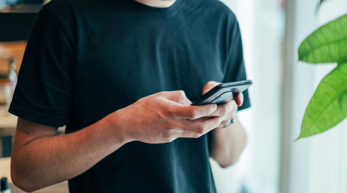 Close-up of a person holding and using a smartphone indoors.