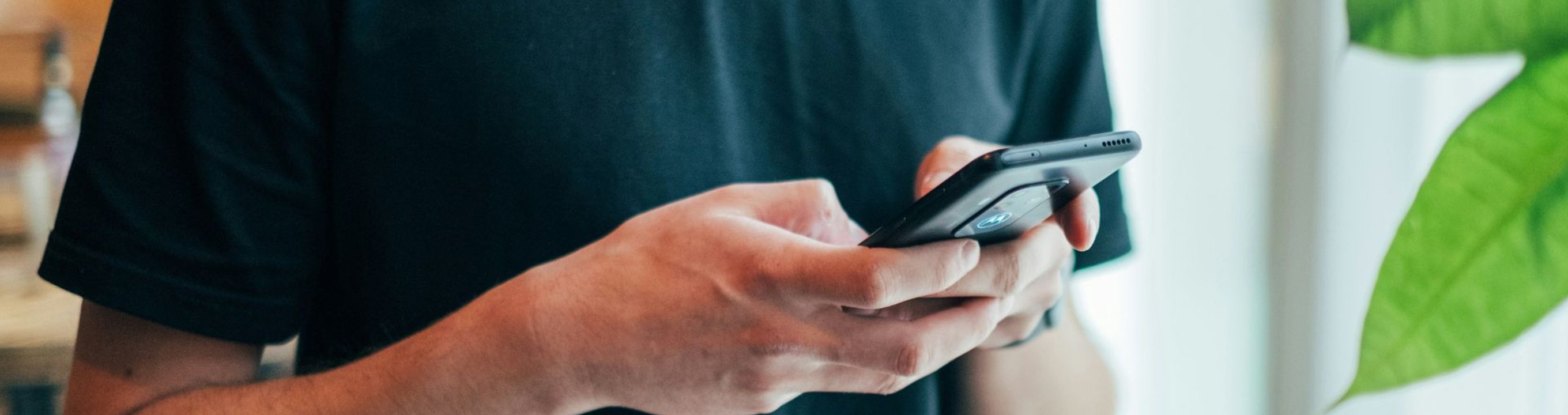 Close-up of a person holding and using a smartphone indoors.