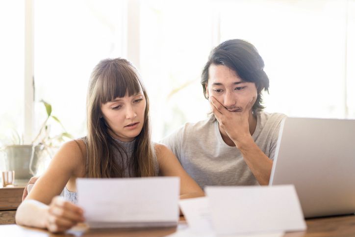 Two people reviewing documents together at a table beside a laptop