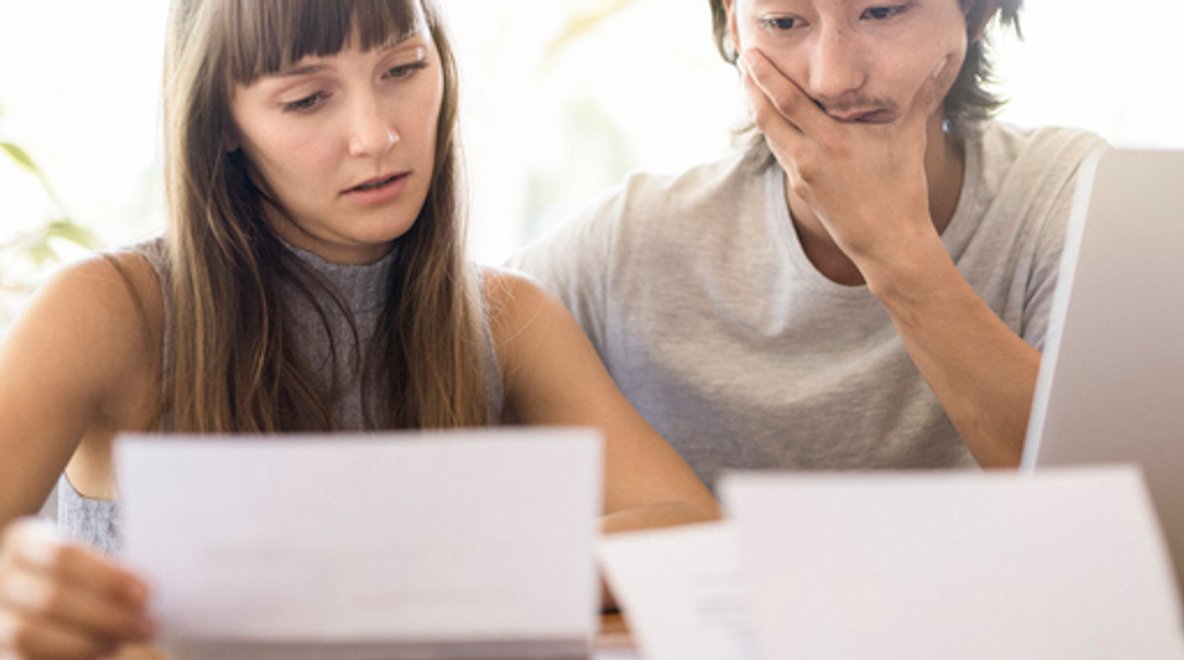 Two people reviewing documents together at a table beside a laptop