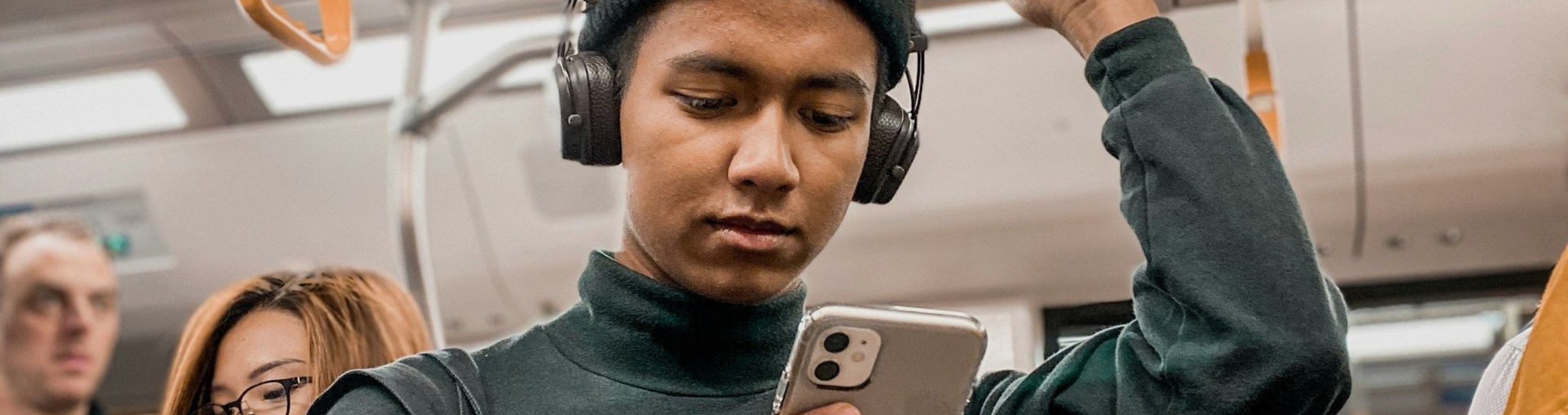 Person standing in public transport and using a smartphone.