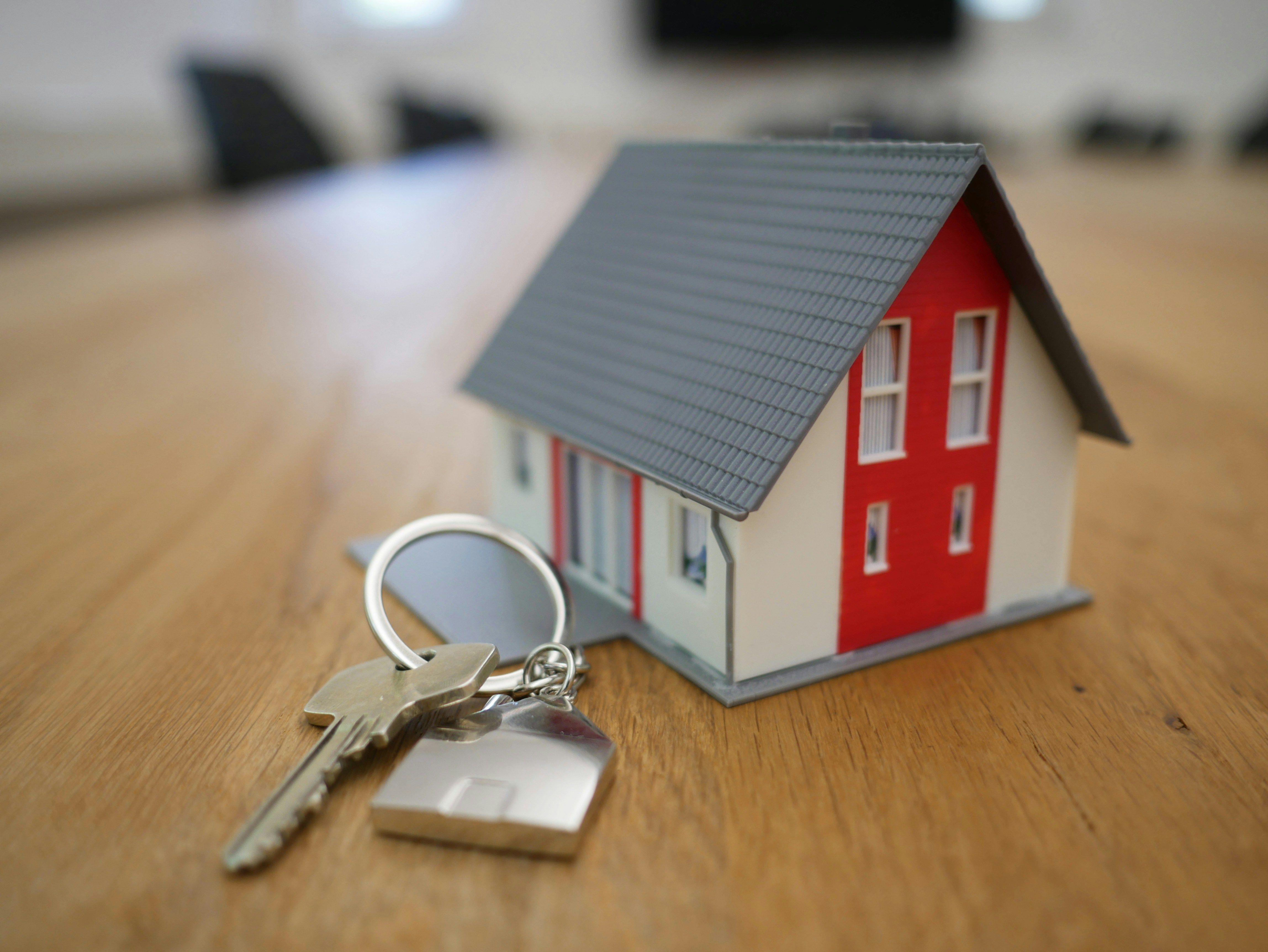Model house with a set of keys on a wooden table.