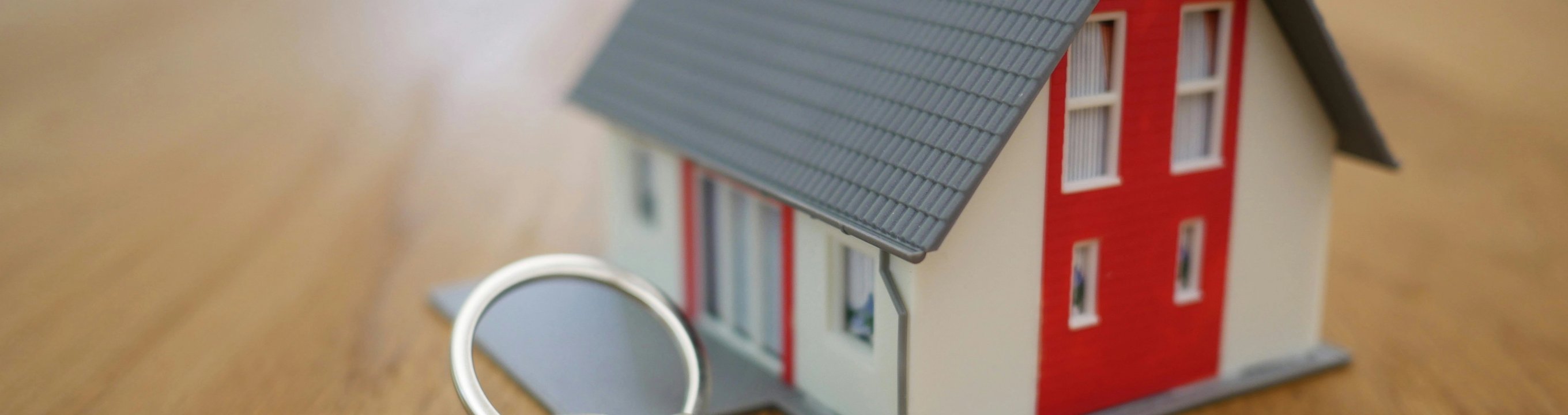 Model house with a set of keys on a wooden table.